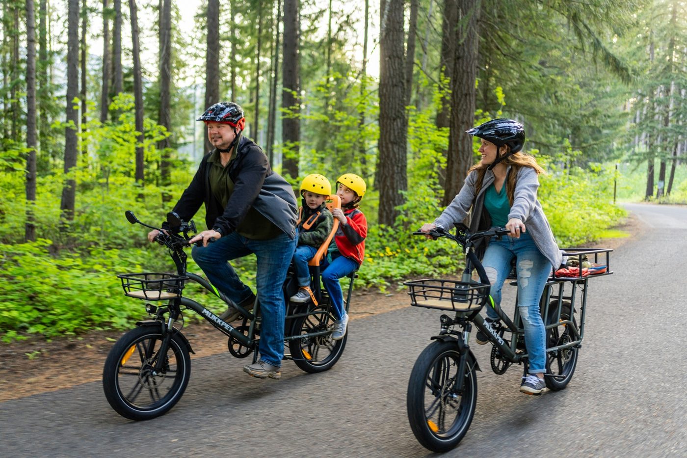 Family riding cargo e-bikes with two children seated on the rear